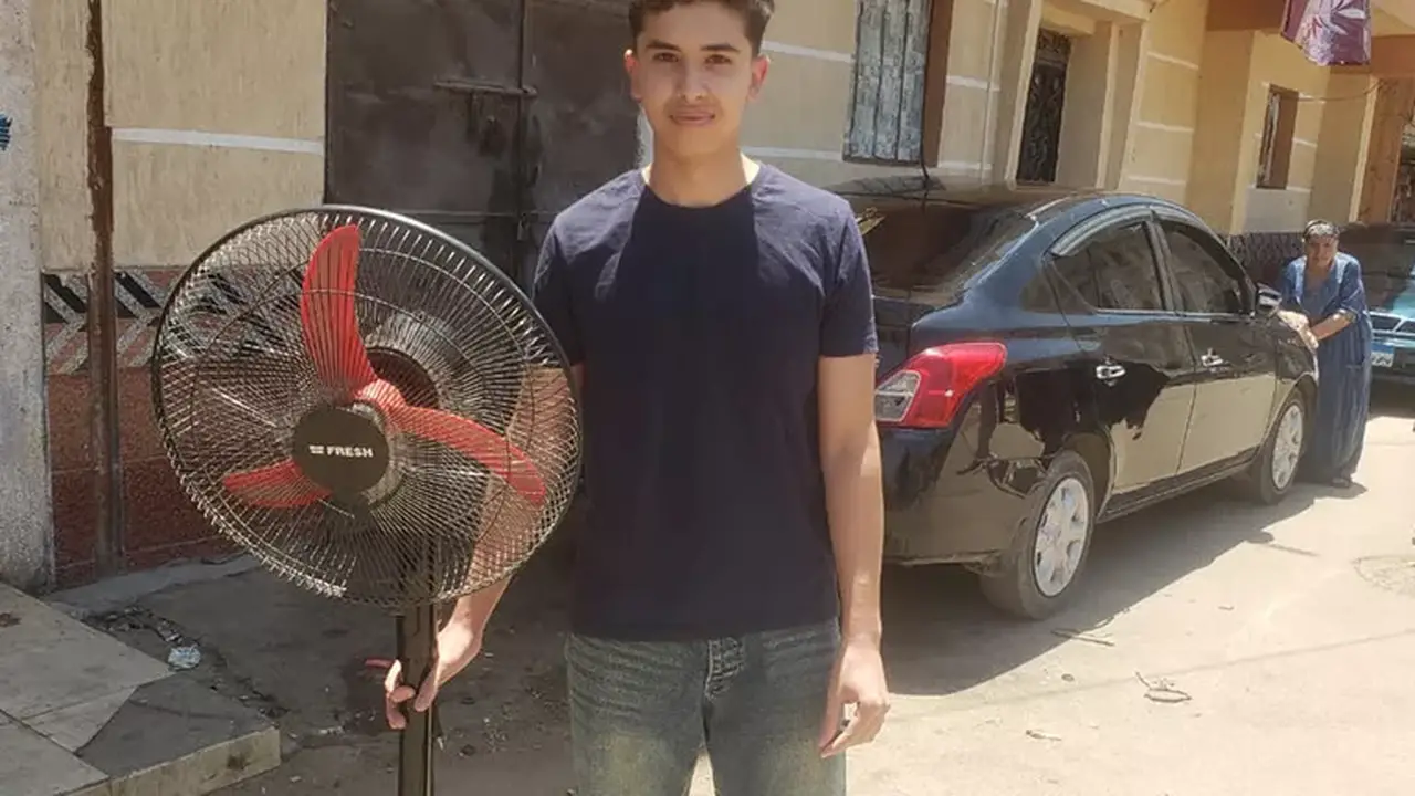 شاب يحمل مروحة لشقيقته لدعمها أمام لجنة امتحانات الثانوية بالبحيرة